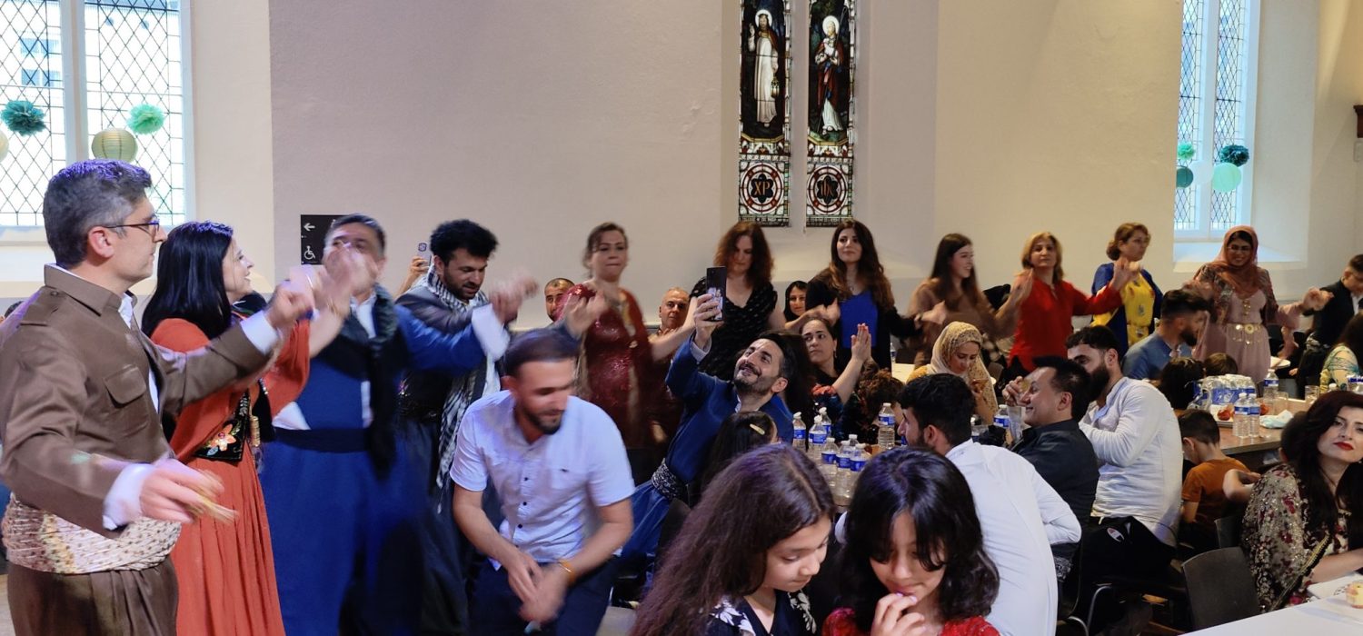 A photograph of people at an event with the Welsh Refugee Council and Kurdish All Wales Association.